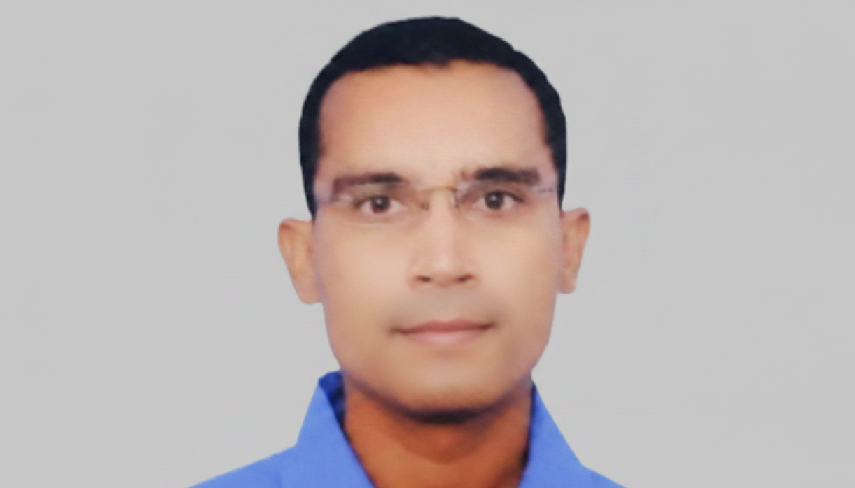 Man wearing glasses and a blue shirt against a gray background